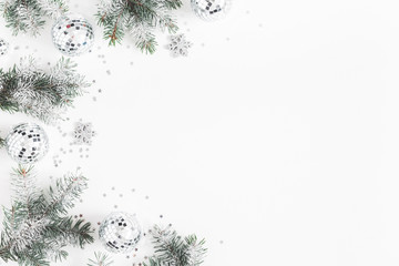 Christmas composition. Frame made of fir tree branches, silver decorations on white background. Christmas, winter, new year concept. Flat lay, top view, copy space
