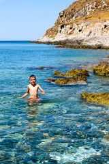 Little boy swims in mediterranean sea near rocks, Monemvasia, Greece