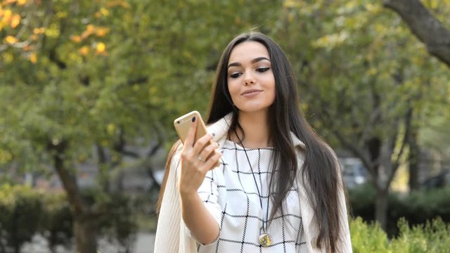 Young beautiful brunette business lady making selfie in the park.
