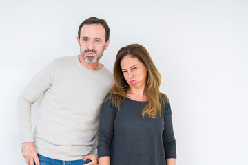 Beautiful middle age couple in love over isolated background puffing cheeks with funny face. Mouth inflated with air, crazy expression.