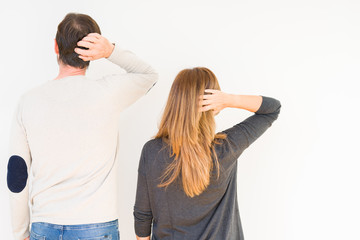 Beautiful middle age couple in love over isolated background Backwards thinking about doubt with hand on head