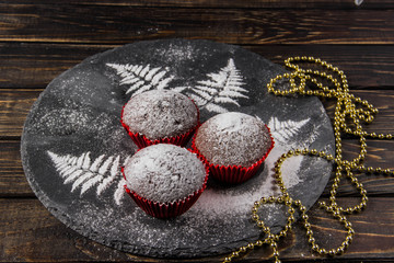 Chocolate muffins on a dark background with icing sugar