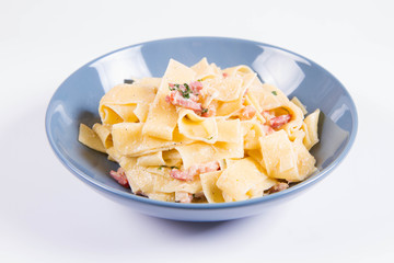 Pappardelle Carbonara on a blue plate on a white background