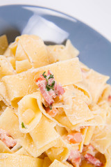 Pappardelle Carbonara on a blue plate on a white background