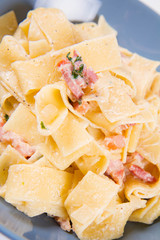 Pappardelle Carbonara on a blue plate on a white background