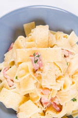 Pappardelle Carbonara on a blue plate on a white background