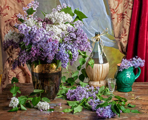 bouquet of lilacs on the table with a bottle and a vase