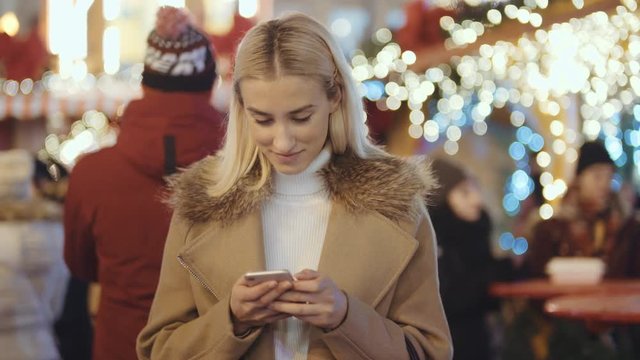Woman using smartphone on christmas market.