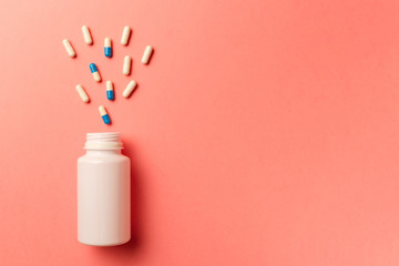 Assorted pharmaceutical medicine pills, tablets and capsules and bottle on coral background. Top...
