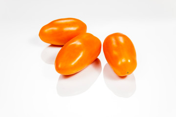 Orange cherry tomatoes isolated on white reflective background