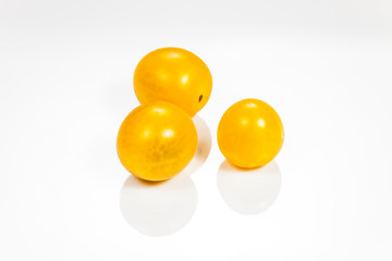 Yellow cherry tomatoes isolated on white reflective background