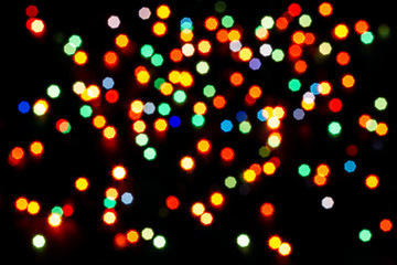 Abstract multicolor bokeh texture on black background. Defocused sparkles.