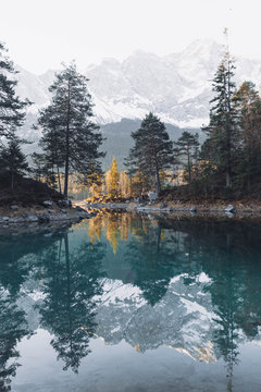 Snow capped mountains and trees reflected on the water