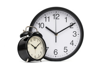 Black vintage alarm clock on the background of modern office hours. Black alarm clock and office clock on a white background. Business concept