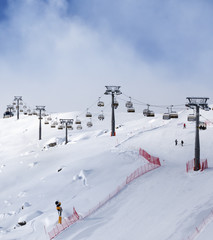 Fototapeta na wymiar Snowy ski slope and ski-lift at sunny winter evening