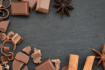 Broken chocolate pieces and chocolate shavings on a dark background. Top view with copyspace for your text