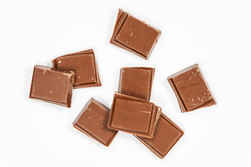 Milk chocolate pieces isolated on white background, top view