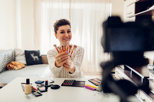 Young woman professional beauty vlogger or blogger recording make up tutorial using camera and tripod