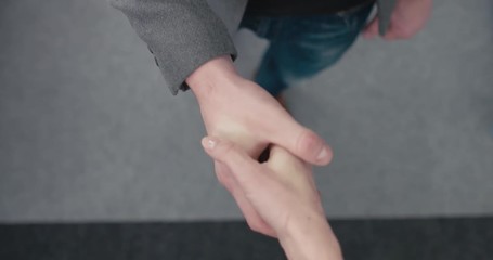 POV Business male and female partners shaking hands as a symbol of unity, overhead top view. 4K UHD