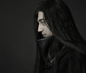 Stylish handsome Young man. Caucasian man's portrait. Sexy man in black clothes with dark long hair.