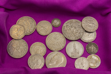 Twentieth-century silver coins on a purple velvet napkin in a casket, close-up, collectible coins, Soviet rubles, German marks, Russian and German empires. Wealth and prosperity concept