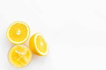 Glass of cold orange juice near halfs of fresh oranges on white background top view copy space