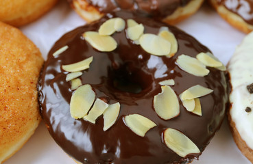 Closed up mouthwatering chocolate glazed doughnut topped with sliced almond 