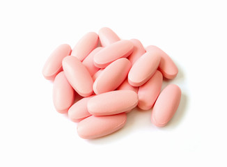 Obraz na płótnie Canvas Pile of light pink color oval shaped pills isolated on white background 