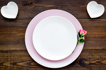 Simple color table setting for celebration with roses, pink plates and wineberry on wooden table background top view mock up