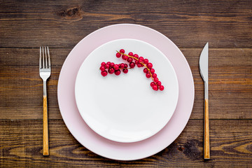 Simple color table setting for celebration with wineberry, white plates and wineberry on wooden...