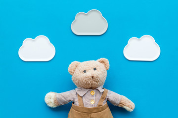 Toys for newborn baby set with teddy bear and clouds on blue background flat lay