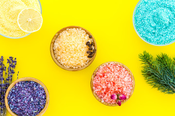 Aromas of bath salt. Lemon, coffee, rosemary, rose, lavender near bowls with colorful bath salt on yellow background top view