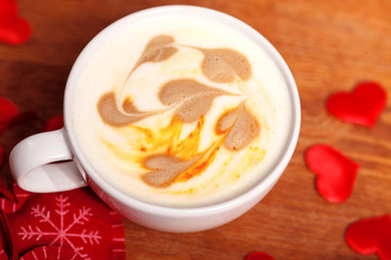 Valentine's day background. A white Cup of cappuccino coffee with a latte art in the form of hearts. Coffee on a wooden table covered with red hearts. Meeting with your loved one over a Cup of coffee