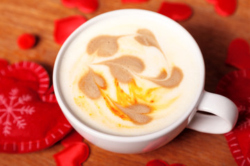 Valentine's day background. A white Cup of cappuccino coffee with a latte art in the form of hearts. Coffee on a wooden table covered with red hearts. Meeting with your loved one over a Cup of coffee
