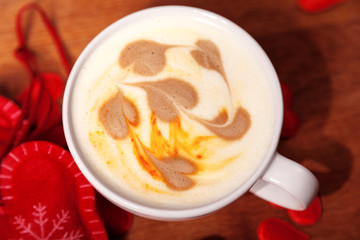 Valentine's day background. A white Cup of cappuccino coffee with a latte art in the form of hearts. Coffee on a wooden table covered with red hearts. Meeting with your loved one over a Cup of coffee