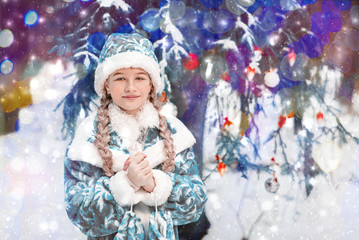 Snow Maiden in the forest. portrait of a little girl in winter in elegant festive costume. the child warms his hands. happy new year