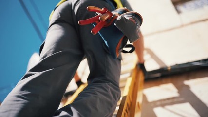 Workman Wearing High Visibility Clothing and Tool Belt Climbing a Ladder - Slow Motion Close-Up - Powered by Adobe