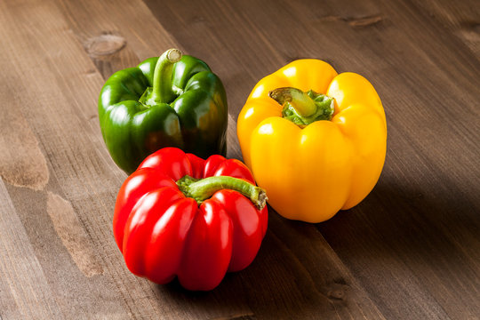 Fresh bell peppers isolated on wooden cutting board