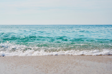 Fototapeta premium Waves with foam hitting sand on the tropical beach texture.