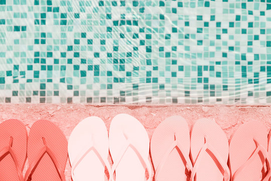 Flip flops near a pool. Living coral theme - color of the year 2019