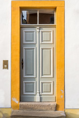 Holztür mit Verzierungen und ornamenten und Oberlicht eines restaurierten Fachwerkhauses mit Zarge aus gebürstetem Sandstein und gelber Fasche
