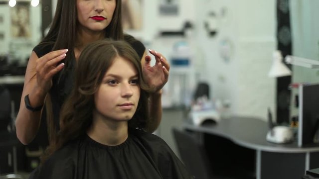 Close-up shot of a woman having her hair straightened in hair salon. Curling iron Shot in slow motion. hd