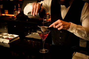 Young bartender preparing a delicious cocktail at the bar of a cocktail bar.