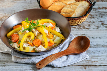 The soup of barley and vegetables on the white rustic background.