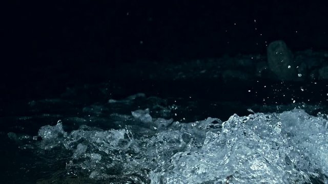 Slow motion of waves on dark water surface with play of flecks of bright light close up. Amazing dramatic natural background. Shooting with 180fps. Epic mystical and magic night view. Crystal clear