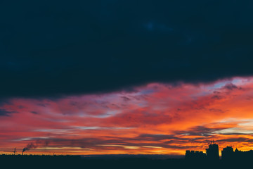 Cityscape with wonderful varicolored vivid dawn. Amazing dramatic multicolored cloudy sky above...