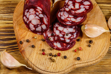 Sliced salami sausage on cutting board on wooden table. Top view