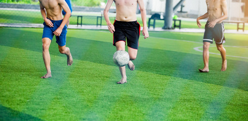 Soccer players not wearing a sport shirt and barefoot do trap and control the ball for shoot to goal