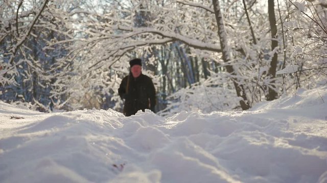 Hunter walking in the snowy winter forest. Winter hobby, sun, hunting concept.