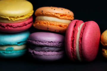 Pile of sweet and colourful french macaroons on black background.